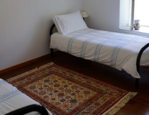 Two single beds in a room with a timber floor and rugs